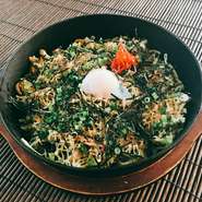沖縄風炊き込みご飯・じゅーしーを使ったビビンバ。具は辛子菜、特製キムチ、もやしのナムル、温泉卵。熱々鉄板でよく混ぜて召し上がれ。