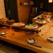 季節によって替わるおばんざいが、ずらっと並ぶカウンター席はほっこりとした温かい空間。大皿に美しく盛り付けられた料理の一皿一皿はどれも食欲をそそります。料理に合わせて酒を選ぶ、会話も弾む楽しい時間です。