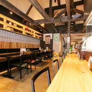 昭和レトロな雰囲気と大きな吹き抜けが印象的な店内。カウンター席からテーブル席、坪庭の景色が楽しめる半個室のボックス席など、幅広い年代のゲストが落ち着いて過ごせる工夫が随所に感じられます。