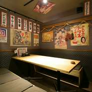 秘密基地へと続くような階段をワクワクしながら下りきると、そこには大漁旗が掲げられた活気ある空間！　適度な喧噪が心地よく、肩肘張らずに寛げます。またカウンター席もあり、一人でも利用しやすい雰囲気です。