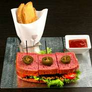 旨みの詰まった肉をふっくらしたトーストではさみました。トーストはラズベリーとビーツを練り込んでいるため、ビビッドな赤が印象的。ピリッと辛いスパイシーなソースが、いいアクセントになっています。				