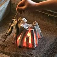川魚の塩焼き(夏は鮎。他の季節は岩魚)。各お部屋に必ずある囲炉裏でお焼き致します。