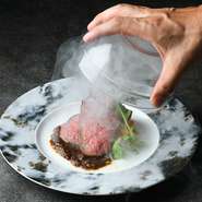 厳選した「牛みすじ」を使い、じっくり低温で仕上げるローストビーフです。お客様の目の前で、瞬間スモークによって提供。ビジュアル的にも驚きを与えくれる、目でも舌でも美味しいメニューです。