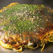 地元で育った店主だからこそ本場の味を知り、本場の味に仕上げるお好み焼き。見事な手さばきで豪快に焼き上げ、仕上げにソースをたっぷり。鉄板にこぼれたソースがこうばしい香りを放ち、ますます期待が膨らみます