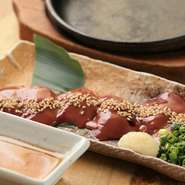 軍鶏の新鮮な白レバーをアツアツの鉄板で両面を軽く炙りごま油塩でお召し上がり頂きます。口の中でとろける食感は絶品です。