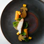 北陸産の白身魚を主役に、皮目は香ばしく中はジューシーにポワレ。カボチャは赤皮甘栗かぼちゃ、コリンキーなど3種を用い、持ち味を表現。フランス産セップ茸と酢漬けブルーベリーがアクセントに。夏～初秋の一例。