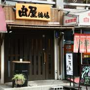 和モダンを感じさせるエントランス。店内はカウンターのみで、美味しい串焼を一人でも気兼ねなく楽しめます。アクセスの良いなんばエリアにあり、仕事帰りのちょい飲みや2軒目にも利用しやすい店。