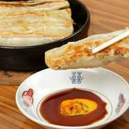 具に芋と山菜を使った【北京餃子房】流餃子。キャベツとニンニクでつくる餃子とは違った独特の食感と、日本人好みに調えた味付けが人気の秘密です。カリッと焼き上げ、熱々の鉄鍋でテーブルへ！