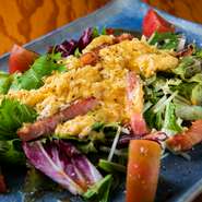 カリカリに焼いたベーコン、卵、シャキシャキとした新鮮野菜のコンビネーションが楽しい『ベーコンとトロトロ卵のサラダ』。オニオンベースの和風ドレッシングと粉チーズ、ブラックペッパーが絶妙なアクセントです。