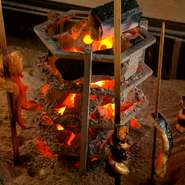 しっとりと落ち着ける臨場感あるカウンター席。目の前に囲炉裏があり、炭火を使ってじっくりと焼く調理風景をみることができます。芳ばしい香り、ジューッという焼ける音、五感で楽しめるのが醍醐味です。