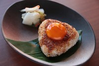 香ばしく焼き上げたおにぎりの上に特製タレで漬け込んだ卵黄をトッピング。