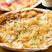 さまざまな酒によく合う、店オリジナルの和風ピザです。ふわりと香るのは、チーズではなくお好みソースとマヨネーズ。いかにも「お好み焼き」といったトッピングとピザ生地の調和に、好奇心を刺激されます。
