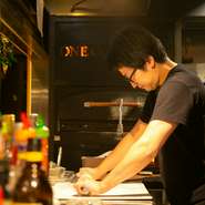 ハンドメイドのピザを、一生懸命手ごねする料理人。力のいる大変な作業中でも決して気を抜かず、実直な姿勢が職人魂を感じさせます。「いつでも気持ちよく食事して欲しいから」と、接客でも笑顔を忘れません。