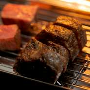 グリルした肉をいったん休ませると、中まで予熱が届いてしっとりした仕上がりに。それを出す直前に再度炭火で炙り、鉄板に肉を乗せ、ゲストのテーブルでお皿にサーブ。気泡を含んだ器も美味しさを引き立てます。