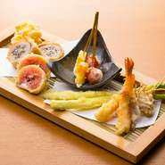 旬の素材を集めた、日替わりの天ぷら五種盛り。魚介の天ぷらは天つゆのほか、ピンクソルトや雪塩など、最適な塩で味わえます。写真は一例で、イチジクの天ぷら、アスパラ、エビ、トマトとチーズ、肉の舞茸巻きなど。