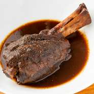 風味に優れた、オーストラリア産仔羊の骨付きスネ肉を豪快な肉料理に。赤ワインでマリネし、ブレゼ（焼いて蒸し煮）を経て軽めの赤ワインと香草を使ったソースで仕上げる。ホロッと柔らかい中に肉の力強さを感じて。