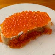 北海道産生筋子が出回る秋～冬の人気の皿。程好い甘みが特長のワイン・ゲヴェルツトラミネールにサッと漬け込んだいくらを、バゲット、リヨン風のチーズディップと共に。ワインの風味がきれいに香る余韻も印象的。