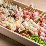 博多の屋台で人気の『野菜巻き』は、レタスや博多万ネギ、旬の野菜などを豚バラやベーコンで巻いた串焼き。色々な野菜と肉の食べ合わせを楽しめる全19種を提供中です。ヘルシーで美味しい看板料理です。