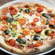 モッツアレラ・チェリートマト・ベーコンをトッピングした王道ピザ。冷めても柔らかい特製ピザ生地に、自家製トマトソース、生バジルを使用して手づくりした自家製バジルソースの香りが、食欲をそそる一品です。