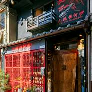 新福島駅から南の方へ歩いて3分ほどの場所にある【中国料理　六徳　恒河沙】。二階建ての一軒家をリノベーションし、ネオン管やアンティーク調の赤い面格子が人目を惹きつけています。