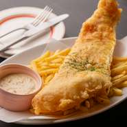 往年のレスラーの名にちなんでつけられたメニュー名の通り、皿からはみ出すほど大きなタラの切り身が使われています。サクッと揚げたインパクトあるフィッシュアンドチップスは、特製タルタルソースでどうぞ。