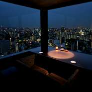 照明をグッと落とした店内は全席カップルシート。どの席からも壮大な夜景が眺められるムーディーな空間です。スポットライトで浮かび上がる料理やカクテルが、夜景と共に幻想的な雰囲気を醸し出します。