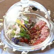 本鮪にほんのり柚子の風味を付けてマリネし、フリーズドライの醤油とオリーブオイルパウダーを添えています。ガラスの器には桜チップのスモークを閉じ込め、開けた瞬間一気に香り広がり幸福を感じられる一皿。
