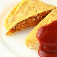 富山の新ブランド米「富富富」を使用。トマトソースとケチャップを合わせた自家製ソースを鉄板の上で混ぜ合わせ、特製のケチャップライスを卵白をメレンゲ状にしたふわふわ卵で包み込んで仕上げます。