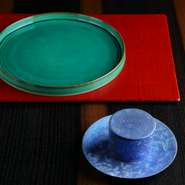 輪島塗りのランチョンに映える、鮮やかな有田焼の器。テーブルの板の色を決めてから、作家の「輪島キリモト」さんにランチョンを特注でお願いし、そこに合う器を選びました。