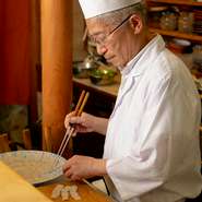カウンター前で黙々と、常に料理をつくり続けている店主