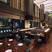 約8メートルの高い天井、床から天井まで届く窓、ゆったりしたテーブル配置で作りだす開放的な空間。シャンパンの泡をモチーフにした空中で輝くオブジェが、優美さを添えています。洗練された大人の空間です。