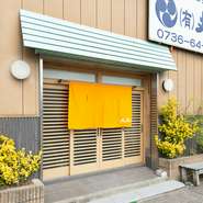 鮮魚店の隣に併設された本館は、ミントグリーンのひさしと明るい山吹色の暖簾が目印です。