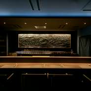 金沢の建築デザイナーが内装を担当。藍色が深い陰影を醸し出し、カウンター席前の壁面には海の渦＆山を表したアートを設え。“海と土”が生む食材の持ち味を引き出した料理に合う、オシャレ＆くつろぎ空間です。