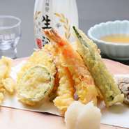 旬の野菜をメインに、海老などその時期のおいしい食材7品を盛り合わせて提供される贅沢な一皿。サクッとした衣に素材の旨みを閉じ込めた揚げたての天ぷらは、格別の味わいです。
