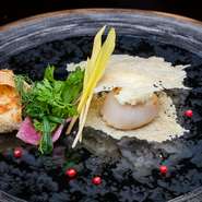 鮮度抜群の北海道のホタテ貝柱と、目の前で焼き上げるチーズのガレット。その日のソースでお楽しみ下さい。味、食感、香りとワクワク楽しめる一皿です。

（写真はコース料理のひとさらです。）