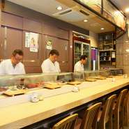 気さくな職人たちが優しく迎え入れてくれる【トップ寿司　本店】。同時に握ってくれるため、待ち時間が短いのも嬉しいポイント。アットホームな雰囲気が漂い、一人でもふらっと立ち寄りたくなる気軽さも魅力です。