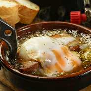 あっつあつでとろーりと伸びるカマンベールチーズと、厚く切った旨味のベーコンに黄身を絡めた絶品！アヒージョ。オイルに浸したバゲットで、ついついワインが進みます。