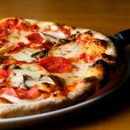 毎日薪を焚く石窯で焼き上げるピザのなかで『サラミときのこのピザ』は、薪の煙のスモークの薫りが引き立つ逸品。手づくり生地のモチモチ感と焼き目の香ばしさも際立っています。焼きたて熱々のうちに、ぜひどうぞ。