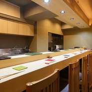 扉を開けると長いカウンター席。木の香りに癒される店内は、白を基調とした清潔感のある雰囲気です。ゆったりとした時間の流れる空間に、心も身体もくつろげます。