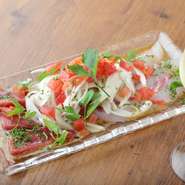 旬の鮮魚を丸ごと仕入れ、店内で捌いて仕上げる『海鮮カルパッチョ』が人気です。季節ごと・日ごとに内容が変わるので、毎回注文しても違ったおいしさが楽しめます。