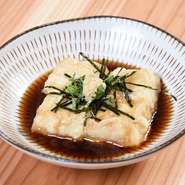 沖縄で豆腐として食されてきたジーマーミー（落花生）豆腐。店では濃厚に仕上げ、一度揚げることで外はサクッと中はもっちり食感に。出汁のきいたつゆでいただきます。