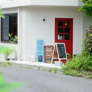 白い建物に真っ赤な扉の小さなお店は、静かな住宅街の丘のふもとにあります。お店を示すのは扉横に立てかけられた看板のみ。すんなりとはたどり着けず、初めて訪れるゲストは迷うことが多いそうです。