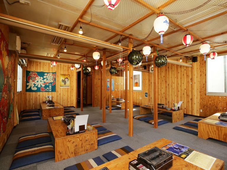 漁具や大漁旗が飾られた、活気に満ちた居酒屋空間