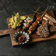 ラムチョップと、牛肉・ラム肉の挽肉で作るスパイシーなアダナケバブ、鶏肉のジューシーなシシュケバブ、メルゲーズ。4種のグリル料理のボリュームある盛り合わせ。スパイシーなハリッサとフライドポテトを添えて。