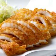 【神戸南京町・民生】からのロングセラーである『名物イカ天』は加古川店でも人気です。最も高級とされるアオリイカを使い、秘伝の味付け衣でカラっと揚げています。