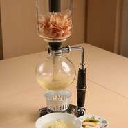 サイフォンの機能は何の料理に使えるか？ 考えてさまざま試してみた結果、カツオ出汁がぴったりだったとか。香りが立ち、美味しい出汁が仕上がる過程もエンターテイメント。出汁茶漬けの超越した美味をご堪能あれ！