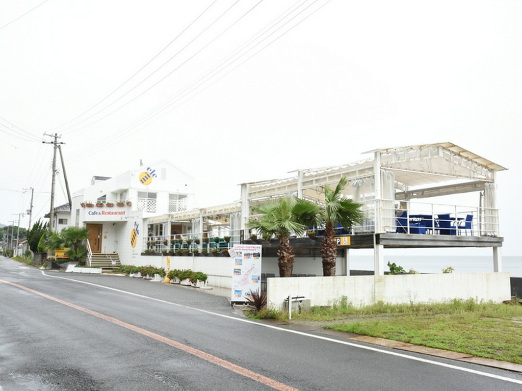 海沿いの白い建物。入口のミツバチをモチーフにしたロゴが目印