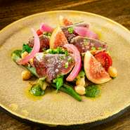 毎日市場に出向いて仕入れるその日の新鮮なカツオを炭火（ジョスパーオーブン）でサッと香ばしく炙り、完熟イチジク・季節野菜と合わせています。スペイン・カナリヤ諸島のソース「モホベルデ」がアクセント。