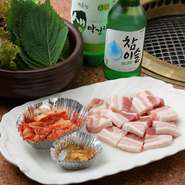 厚さ1cmほどもある赤身・脂・赤身の三段に層が重なったビタミン豊富な豚バラ肉を、エゴマ、ニンニク、キムチなど滋養強壮と美容にいい野菜類でくるんで食べるのが韓国流。栄養バランスの取れたご馳走です。