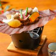 朴葉と自家製のあわせ味噌の香ばしいかおりがふわりと広がり旬の食材を包み込みます。目の前で焼き上げるライブ感を楽しみながら日本酒をかたむけるのは趣深い瞬間です。（季節により具材は変更します）